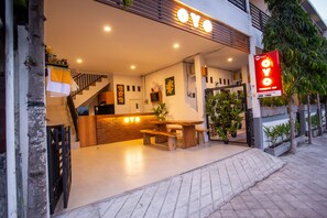 Entrada moderna de hotel com balcão de recepção, escadaria e placa.