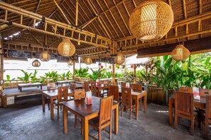 An outdoor restaurant with wooden tables and chairs, bamboo ceiling, and hanging lanterns. - OYO 1207 Pondok 789 (Munggu)