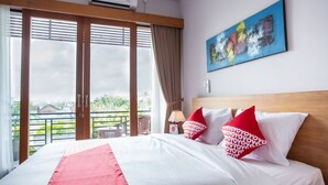 Ein Hotelzimmer mit Bett, einem Gemälde und Blick auf Grünfläche.