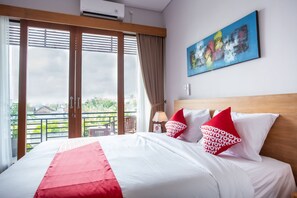 Quarto de hotel com cama, um quadro e vista para o verde.