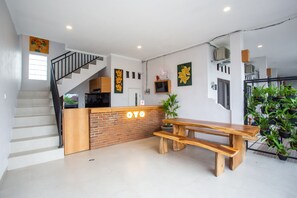 A modern kitchen with a wooden counter, a staircase, and a dining area with a wooden bench. - OYO 1207 Pondok 789 (Munggu)