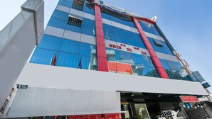 A multi-story building with a prominent red and white facade, large glass windows, and signage for a restaurant named "Srin" and a store named "Calcutta". - OYO 436 Emirates Suites (Bengaluru)