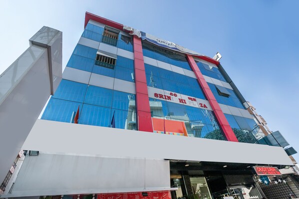 A multi-story building with a prominent red and white facade, large glass windows, and signage for a restaurant named "Srin" and a store named "Calcutta".
