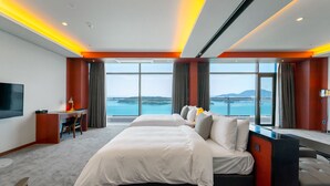 A hotel room with a large bed, a desk, and a TV. It has a view of the sea and mountains. - Hotel JCS Yeosu (Yeosu)