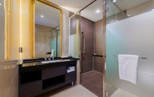 Un baño moderno con un espejo grande, tocador oscuro y ducha con cerramiento de vidrio.