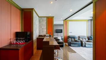 A modern hotel room with a bar area, seating, and a television.