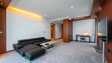 Una sala moderna con un sofá seccional, una mesa de centro, un televisor y un escritorio con una silla.