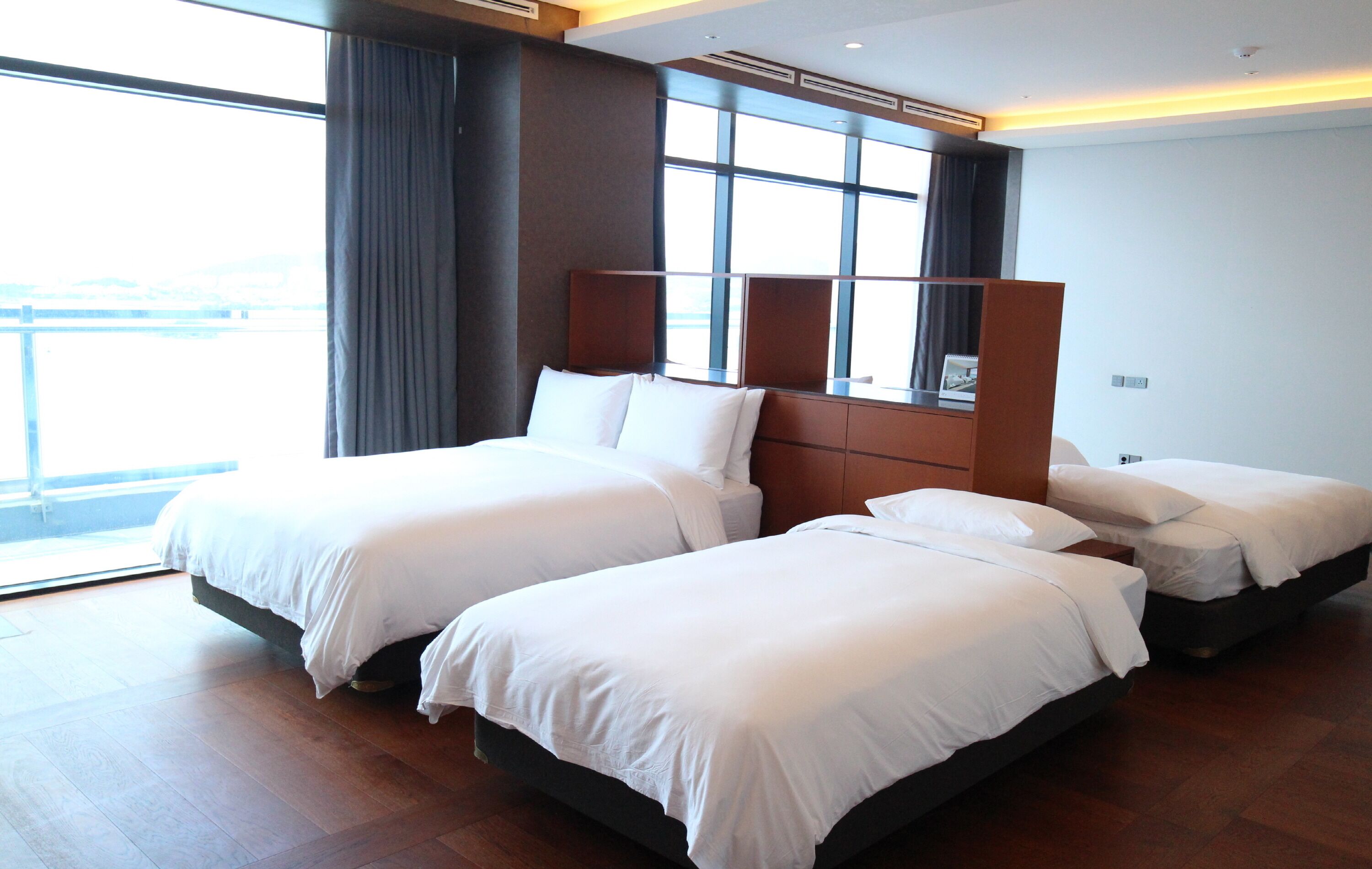 Ett hotellrum med två sängar, ett stort fönster och utsikt över staden.