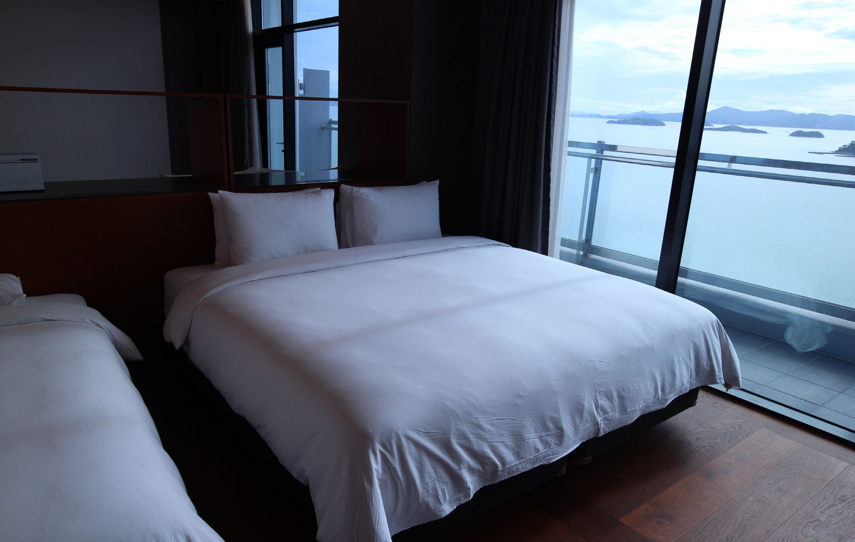 A hotel room with a large bed, a smaller bed, and a window with a view of a body of water and islands.