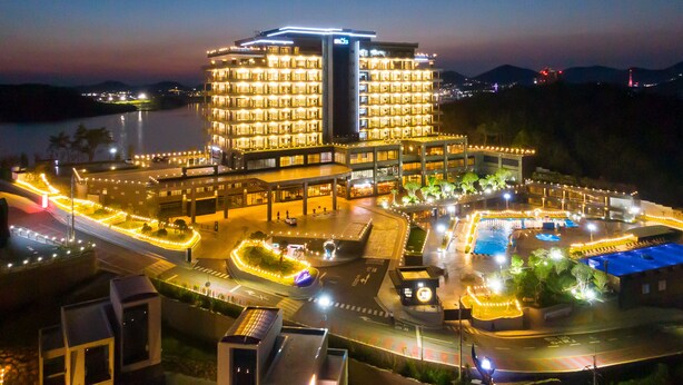 A multi-story hotel with a pool area, surrounded by well-lit pathways and a parking lot. - Hotel JCS Yeosu (Yeosu)
