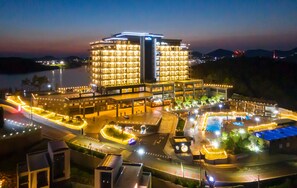 A multi-story hotel with a pool area, surrounded by well-lit pathways and a parking lot. - Hotel JCS Yeosu (Yeosu)
