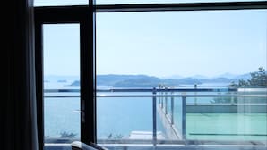 A balcony with a view of a body of water and distant mountains. - Hotel JCS Yeosu (Yeosu)