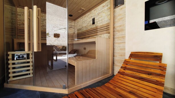 Un sauna avec des bancs en bois et une porte en verre.