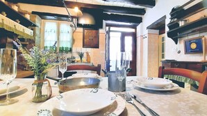 Un coin repas avec une table dressée pour deux personnes, comprenant des assiettes, des couverts et un vase avec des fleurs.