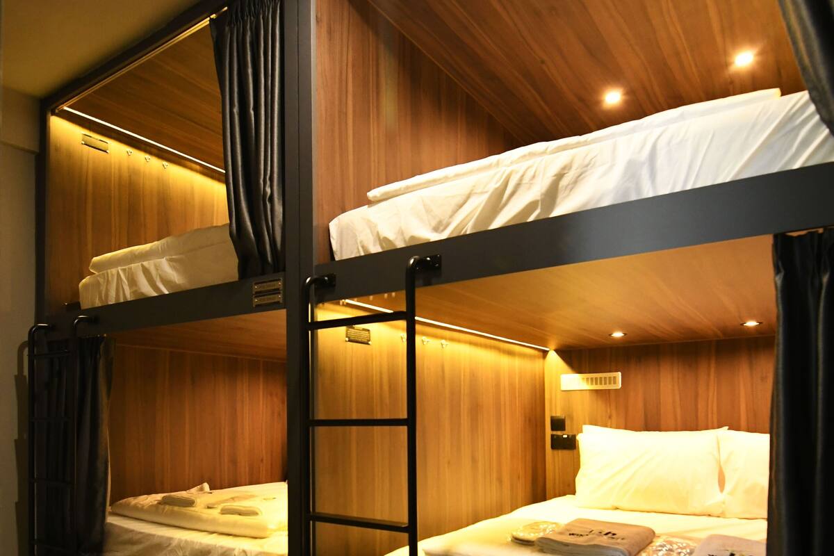 Quarto com beliche, paredes de madeira e chão coberto por carpete.