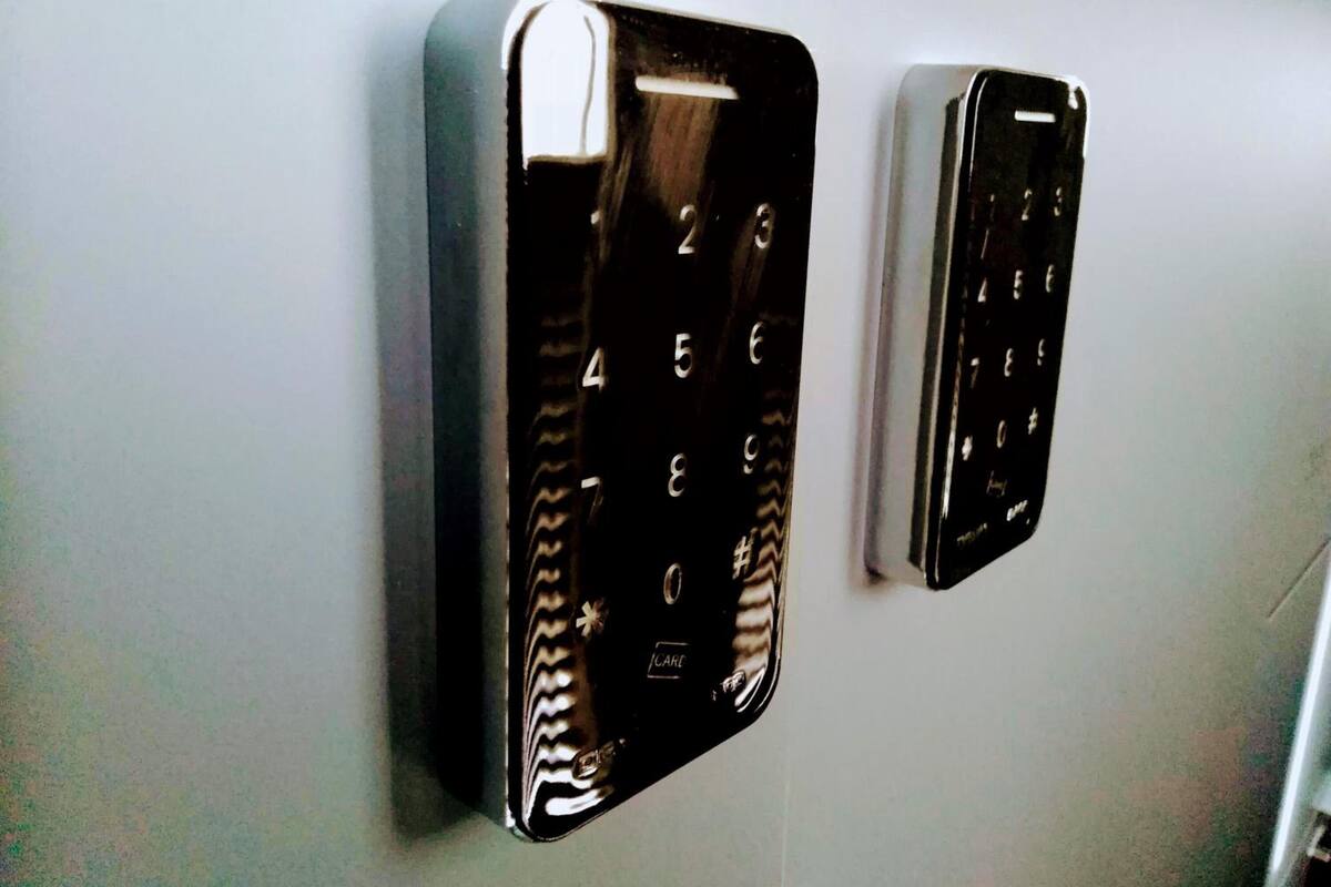 Dois painéis fixados na parede, provavelmente para acesso ao quarto, com acabamento metálico e disposição de teclado numérico.