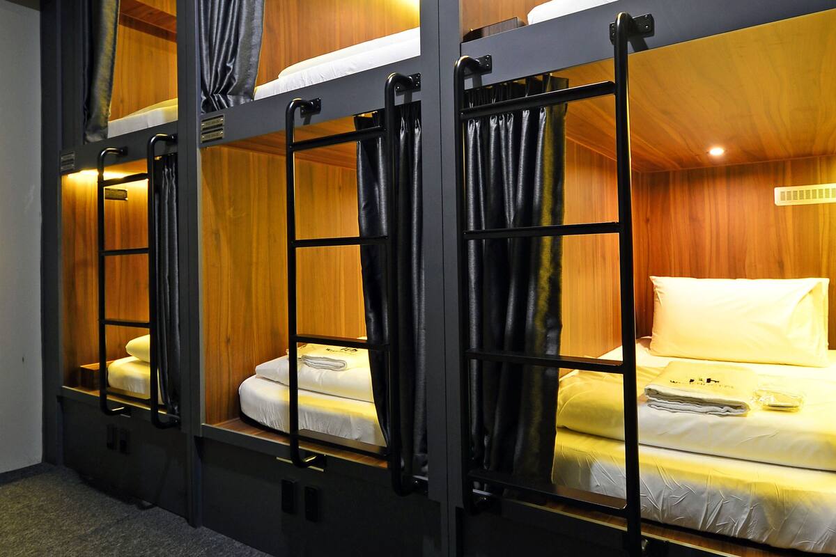 Quarto com beliches, paredes de madeira e cortinas.