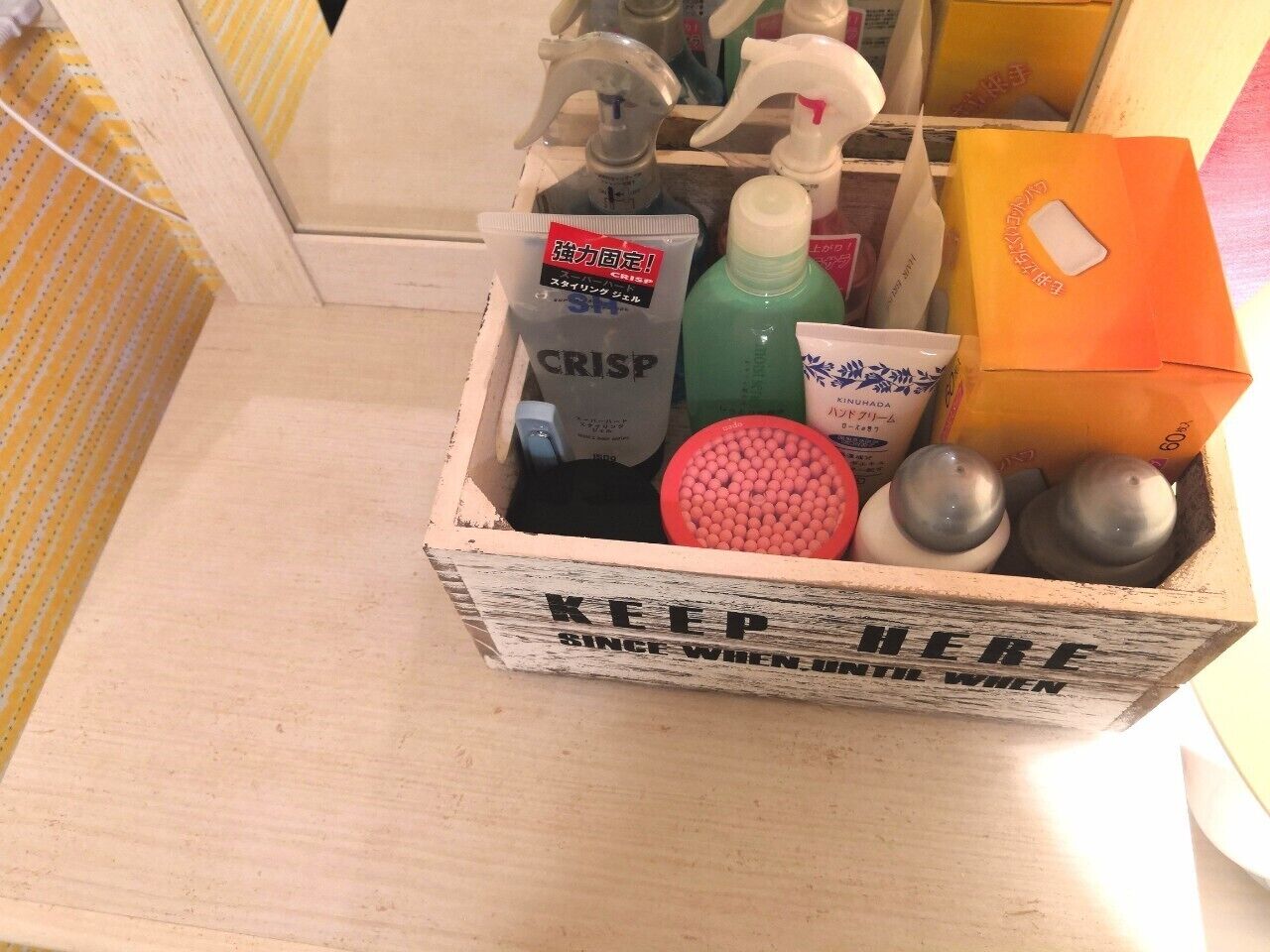 A wooden box containing various toiletries including a tube of CRISP, a green bottle, and a red container.