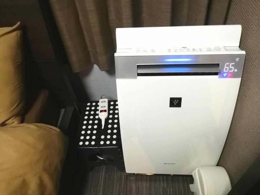 Una stanza con un letto, un termosifone bianco e un pannello di controllo con display digitale.