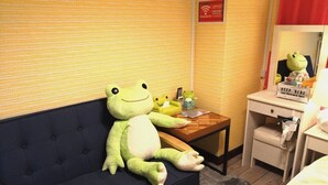 A room with a dark blue sofa, a small wooden table, and a mirror reflecting a frog-shaped object. - Chintai Navi Hostel (Osaka)