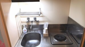 A compact kitchen with a stainless steel sink, faucet, and stove. - Chintai Navi Hostel (Osaka)