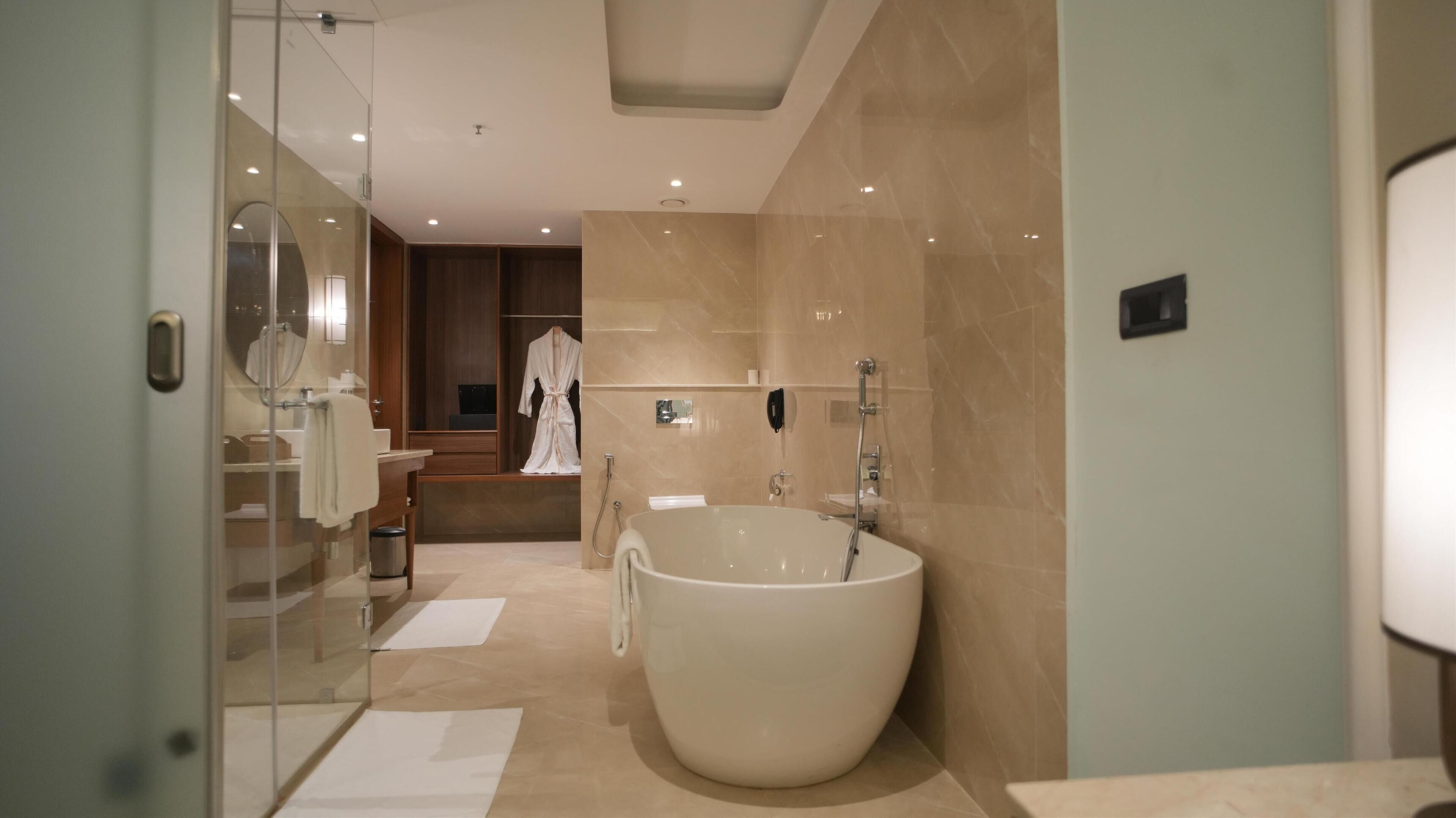 Een moderne badkamer met een vrijstaand ligbad, een glazen douchecabine en een inloopdouche.