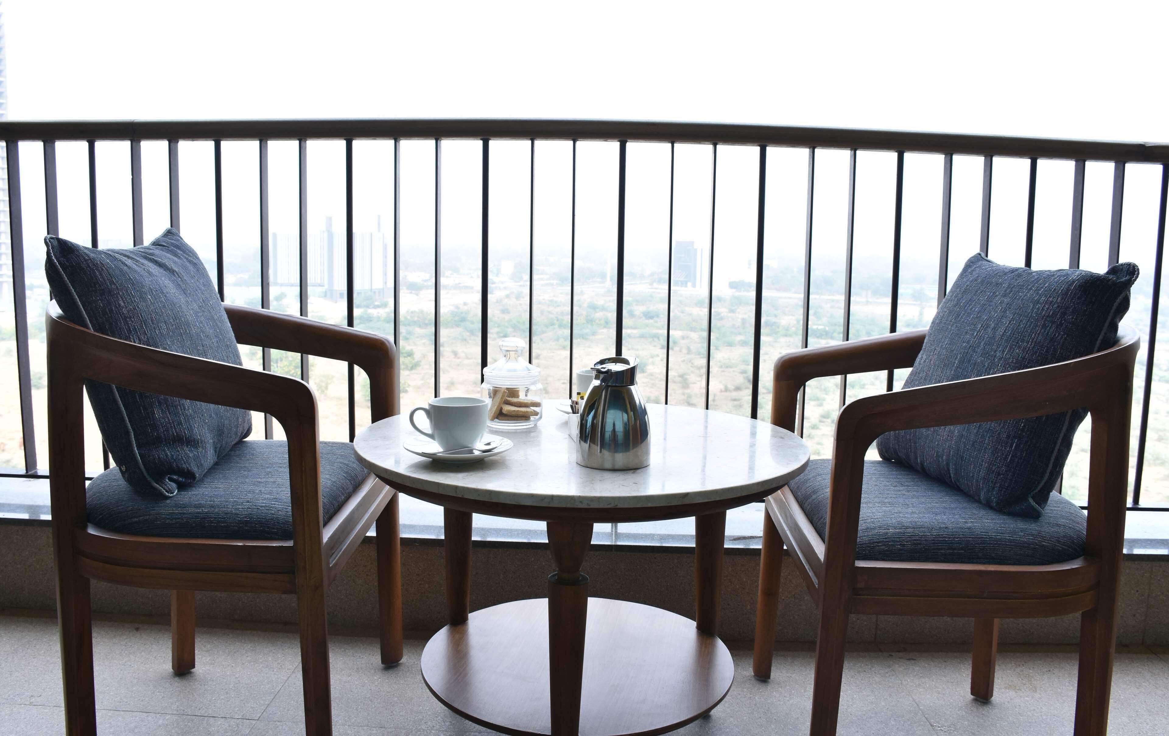A balcony with two wooden chairs and a small round table.