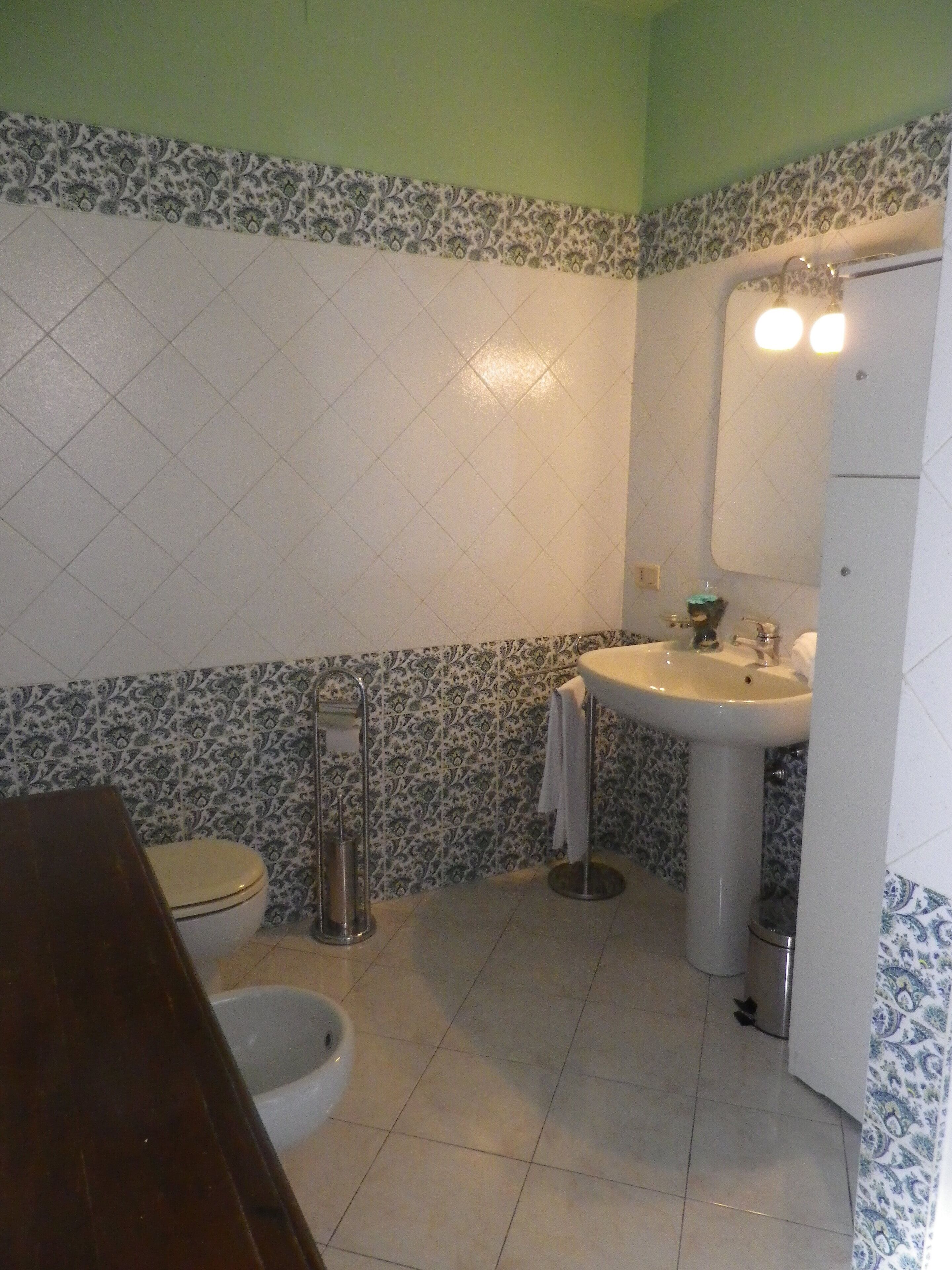 A bathroom with a toilet, bidet, sink, and mirror.