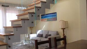 Een moderne woonkamer met een glazen trap, een bank, een lamp en een schilderij aan de muur.