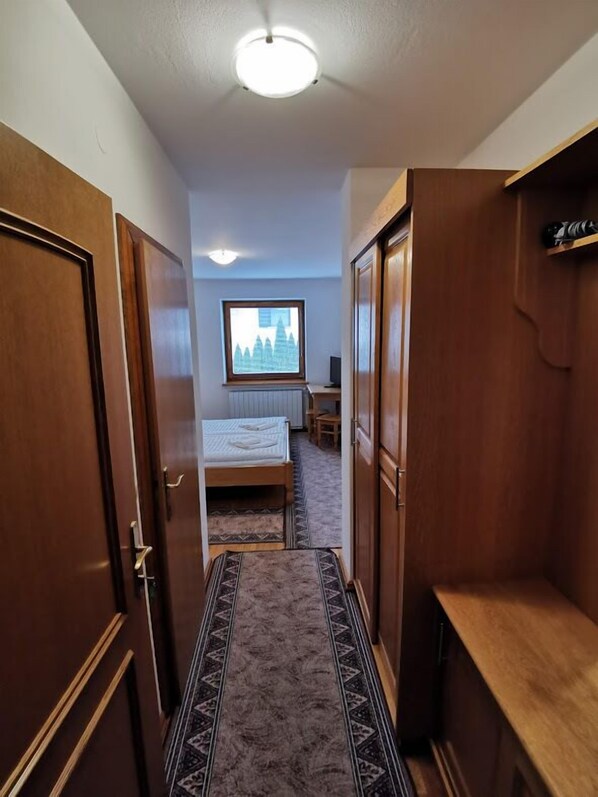 Un pasillo estrecho con puertas de madera y una cama al final.