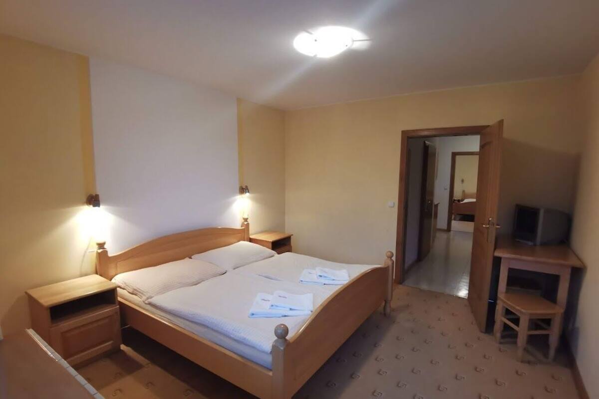 Ein Hotelzimmer mit einem hölzernen Bett, Nachttischen, einem Fernseher und einem Spiegel.