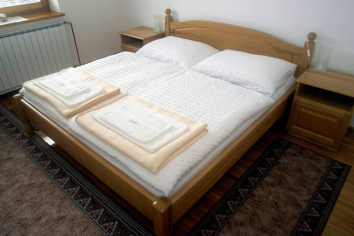 Ein Doppelbett mit Holzbettgestell, zwei Nachttische und ein Beistelltisch.