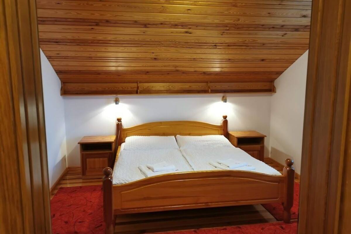 Ein Bett mit Holzgestell, zwei Nachttische und ein roter Teppichboden.