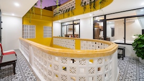 A modern interior with a yellow accent wall, a white decorative railing, and a patterned floor. - The Lit Villa (Da Nang)