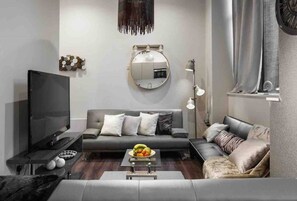 Relax in this stylish living room with a flat-screen TV, comfortable sofa, and a round mirror.