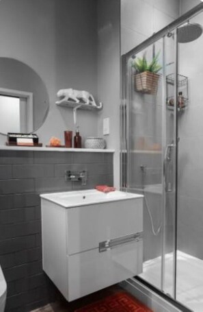 Bathroom features a white vanity, glass shower enclosure, and a potted plant.