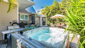 Un jardin avec un jacuzzi, du mobilier d’extérieur et un barbecue.