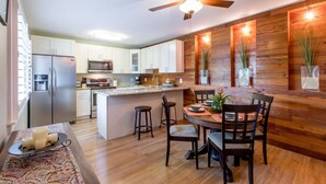 Une cuisine moderne avec des armoires blanches, des appareils en acier inoxydable et un mur d’accent en bois.