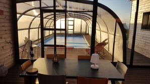 Een kamer met uitzicht op een buitenzwembad door een glazen constructie.