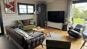 Een woonkamer met een bank, een salontafel, een televisie en een groot raam.