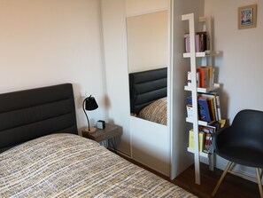 A bedroom with a bed, a bedside table with a lamp, a bookshelf, and a chair. - Keroanne- 6 persons pool & spa sea view (Plomodiern)