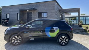 Een zwarte auto geparkeerd voor een modern huis met een houten gevel.