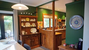 A dining area with a wooden table, chairs, and a counter with kitchen appliances. - Light filled upstairs home minutes from central Hamilton (Claudelands)