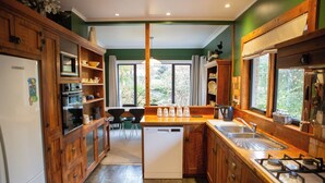 A kitchen with wooden cabinets, a dishwasher, a stove, and a window with curtains. - Light filled upstairs home minutes from central Hamilton (Claudelands)