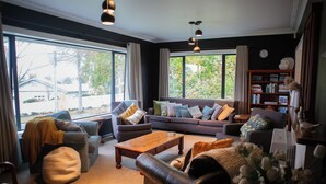 A living room with a sofa, armchairs, a coffee table, and a bookshelf. - Light filled upstairs home minutes from central Hamilton (Claudelands)