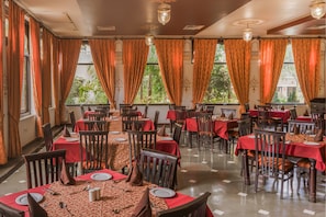 Un restaurante con varias mesas, manteles rojos y sillas de madera.