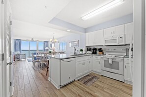 A modern kitchen with white cabinets, a built-in microwave, and a stove. - Large 4 Bedroom Oceanfront Condo in North Myrtle Beach! | Ashworth - 1601 (North Myrtle Beach)