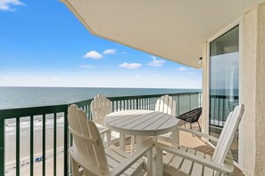A balcony with a table and chairs, a view of the ocean, and a glass door. - Large 4 Bedroom Oceanfront Condo in North Myrtle Beach! | Ashworth - 1601 (North Myrtle Beach)