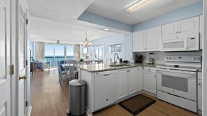 Une cuisine moderne avec des armoires blanches, une cuisinière en acier inoxydable et un grand îlot central.