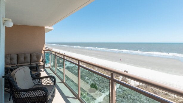 Un balcon avec vue sur la plage et l’océan.